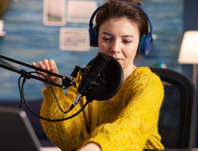 Schmuckbild Eine Frau, die mit Headset und Mikro vor ihrem Laptop sitzt