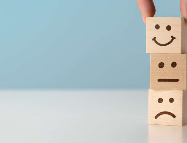 Schmuckbild ein Holzturm aus Klötzen jeweils mit lachendem, neutralen und traurigem Gesicht